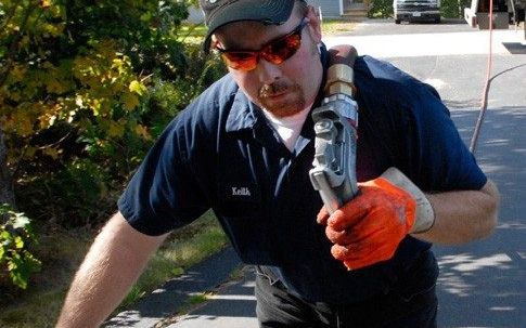 Heating oil driver carrying a delivery nozzle up a driveway on an emergency call