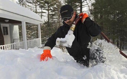 Driver clearing snow from a buried oil tank fill pipe for a same-day delivery